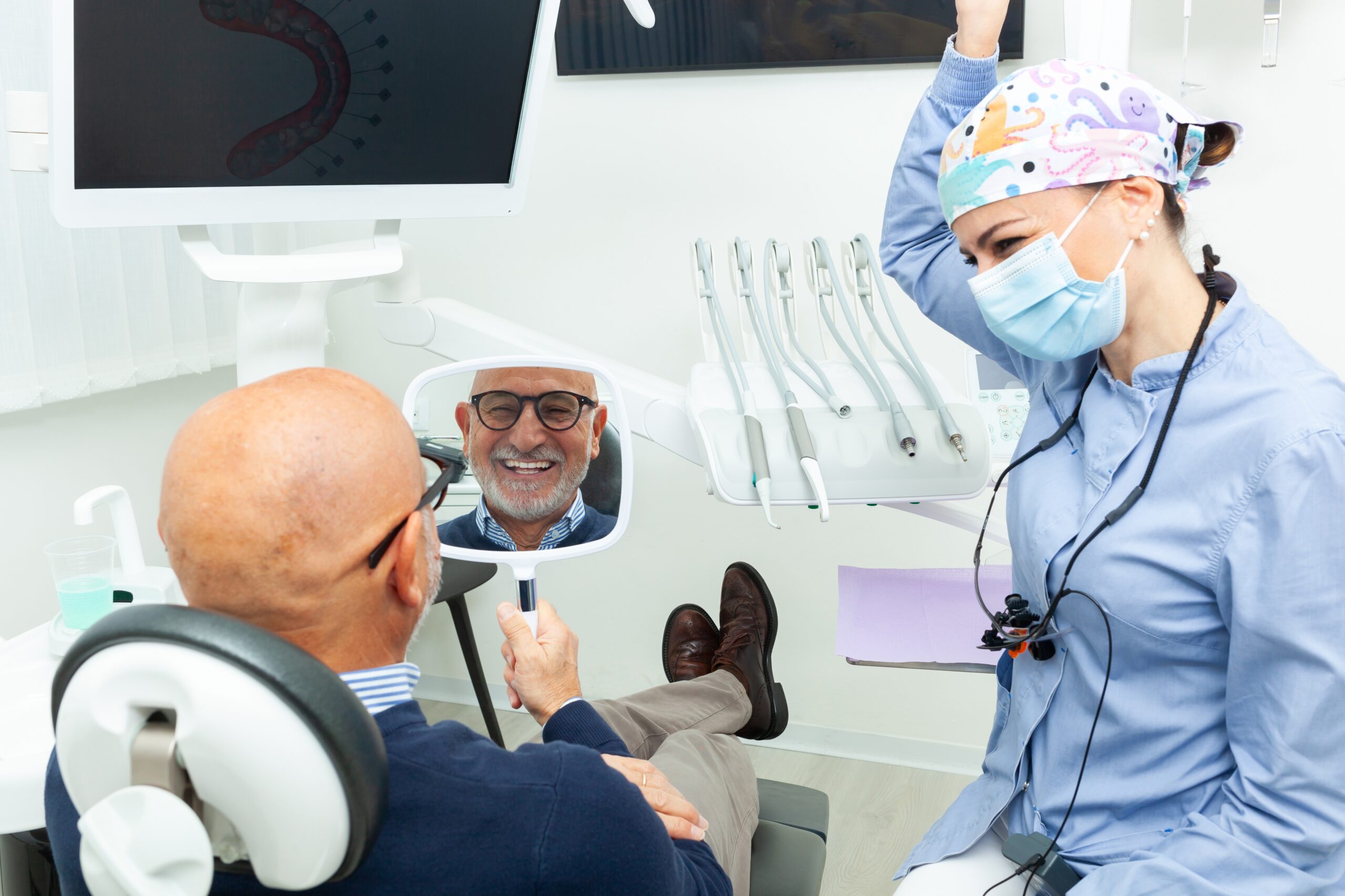 man smiling in a mirror, happy with his dental implants
