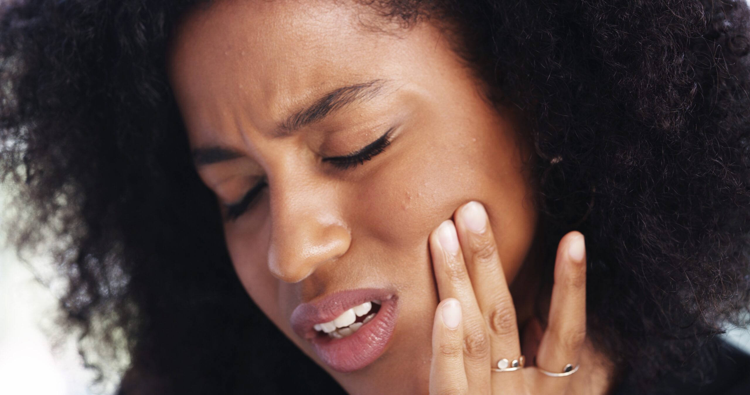 closeup of a woman holding her jaw in serious tooth pain, need for root canal