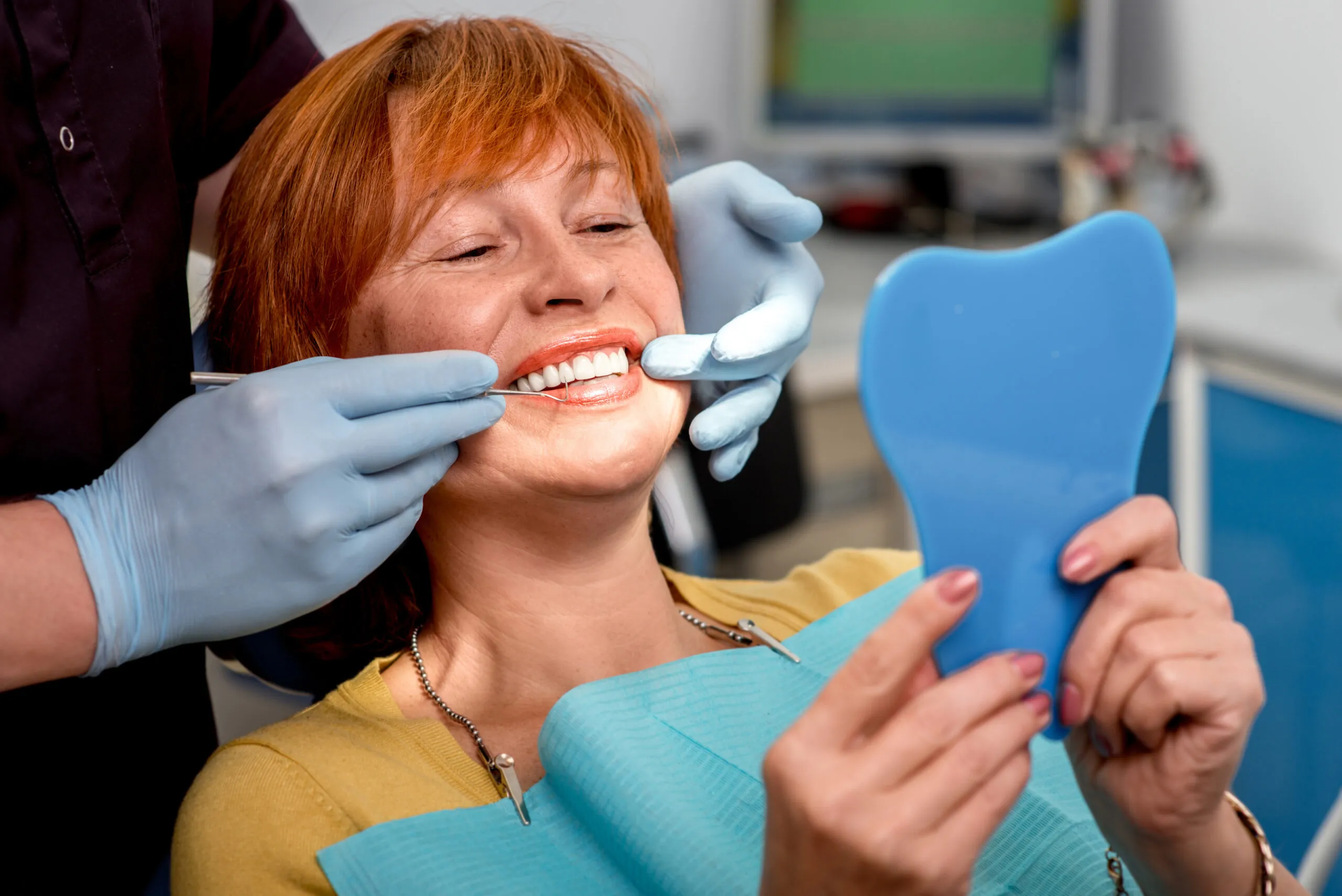 dentist in blue gloves showing a female patient her new dental bridge